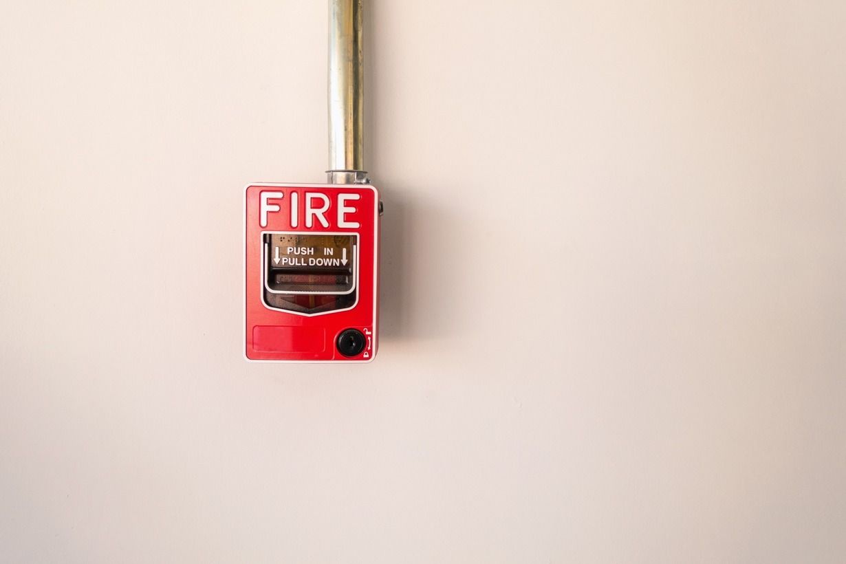 Una alarma de incendios roja está colgada en una pared blanca.