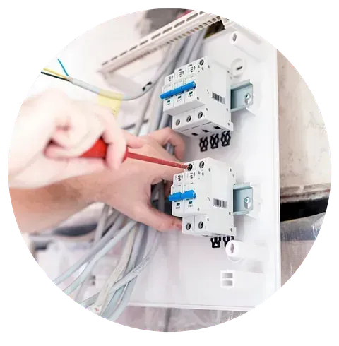 Una persona está trabajando en una caja eléctrica con un destornillador.