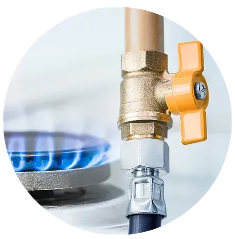Un primer plano de una válvula de gas al lado de una estufa de gas.