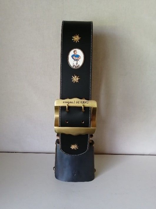 Ein schwarzer Gürtel mit einer goldenen Schnalle trägt das Bild einer Kuh