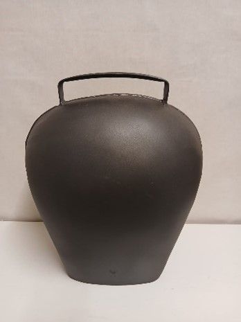 Auf einem Tisch liegt eine schwarze Glocke mit Pelzkragen.