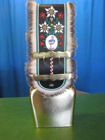 Auf einem grünen Tisch liegt eine kleine Glocke mit einer Schleife.