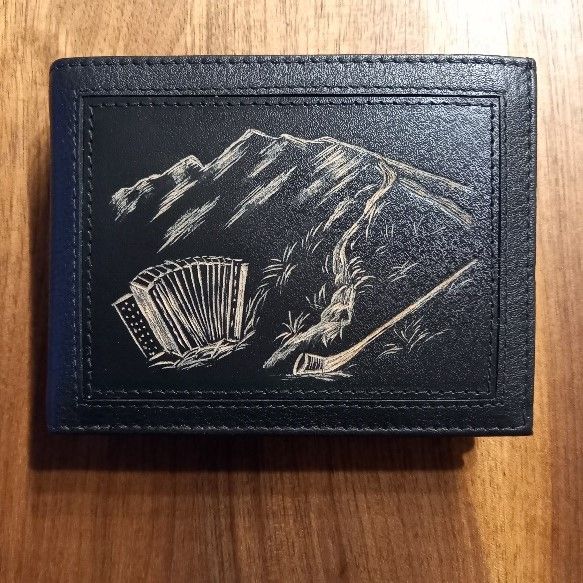Eine schwarze Brieftasche mit einem Bild eines Berges und eines Akkordeons darauf
