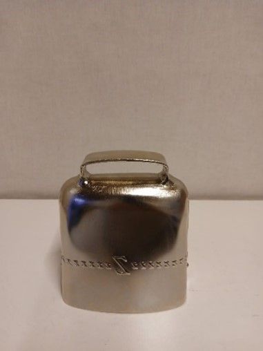 Auf einem weißen Tisch liegt eine silberne Glocke mit Griff.