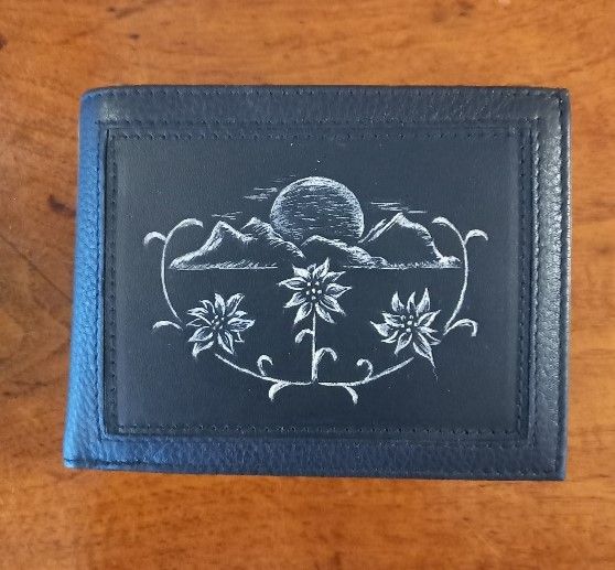 Eine Brieftasche mit einem Bild von Bergen und Blumen darauf