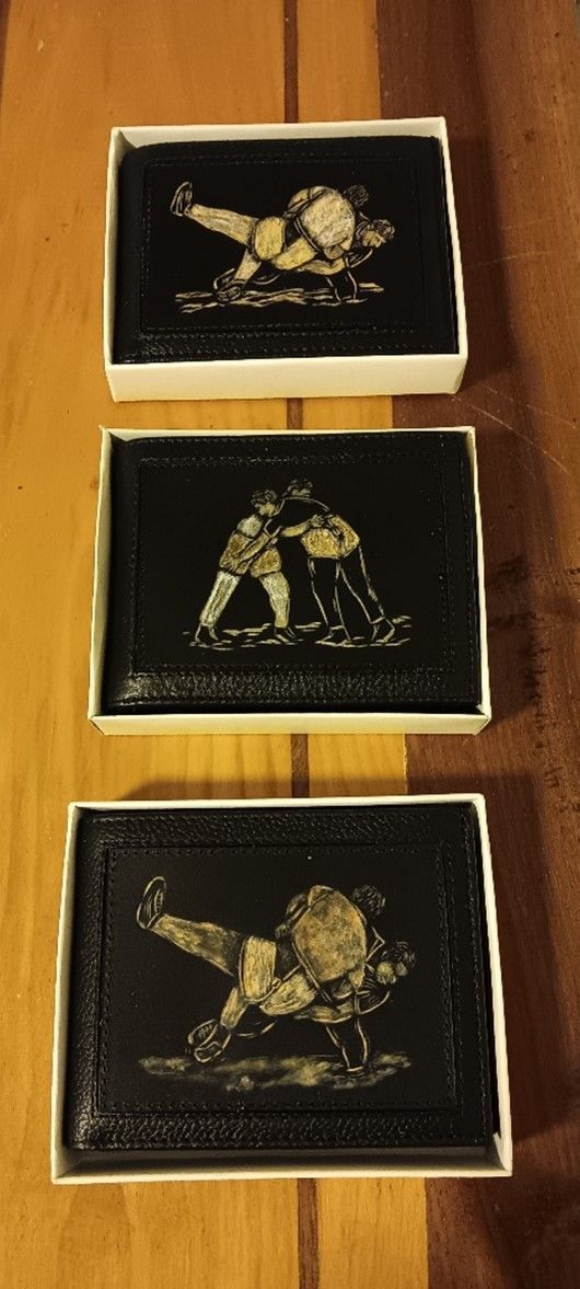 Auf einem Holztisch stehen drei Kisten mit Bildern von Wrestlern.