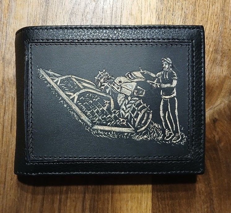 Eine schwarze Brieftasche mit dem Bild eines Mannes, der ein Feld pflügt