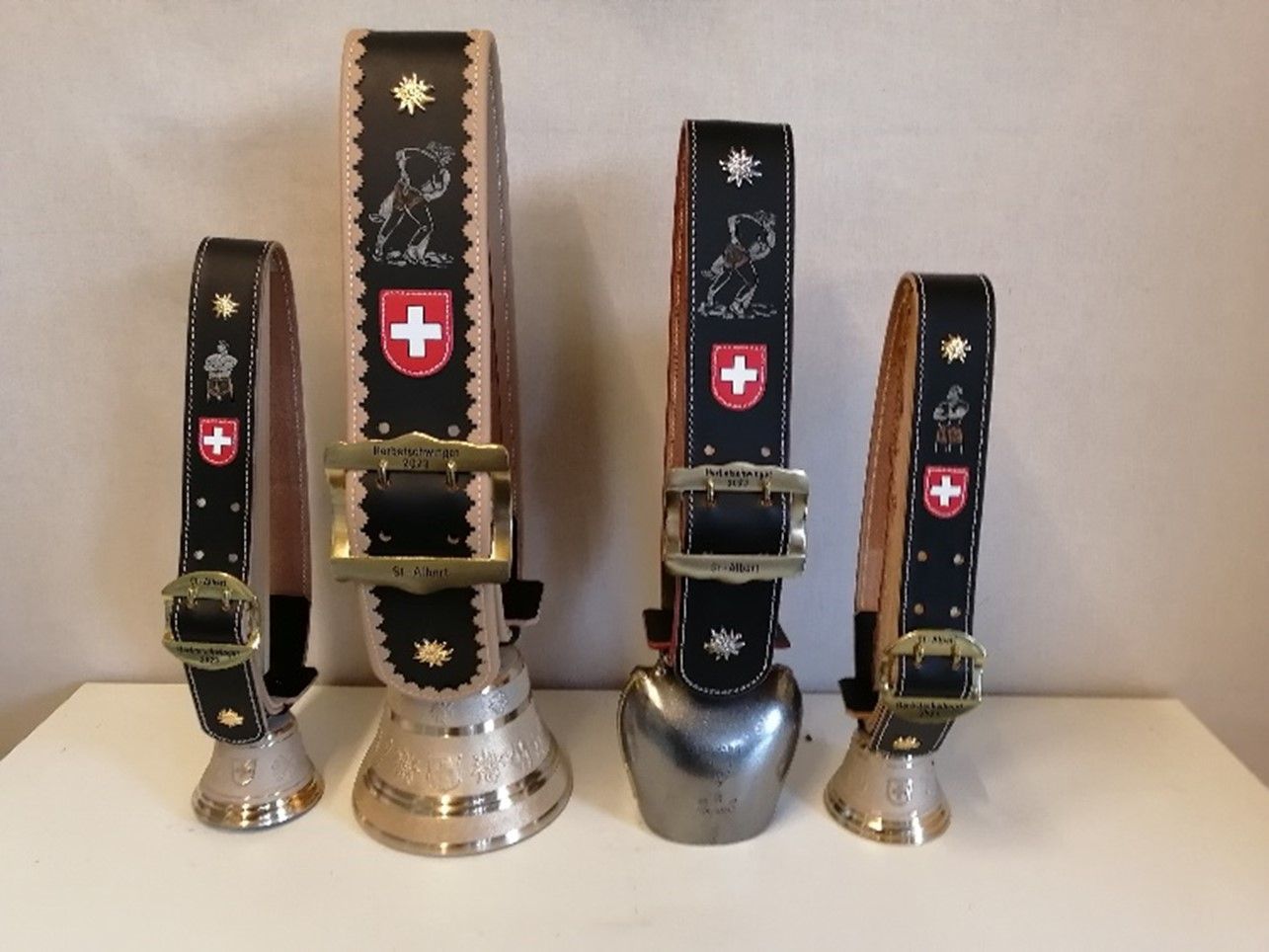 Vier Kuhglocken mit einer Schweizer Flagge darauf