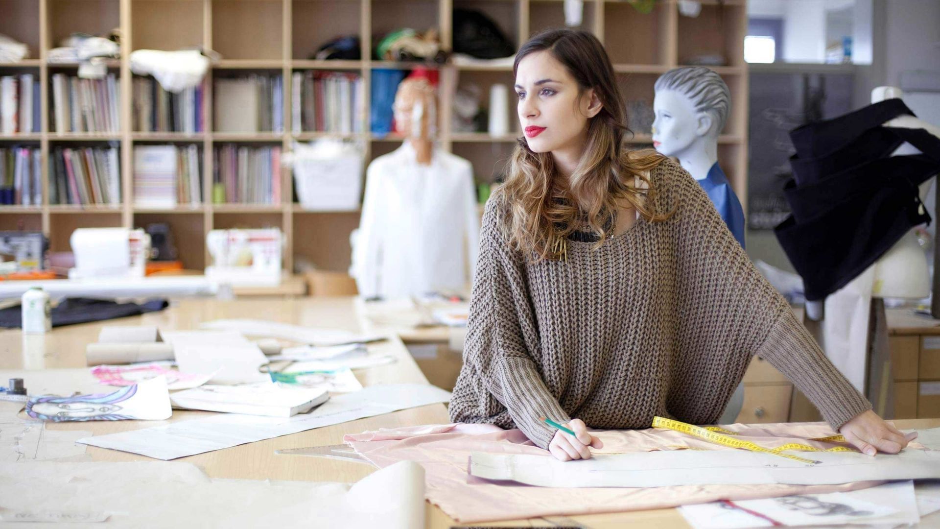 Una mujer está sentada en una mesa en una habitación mirando un trozo de papel.
