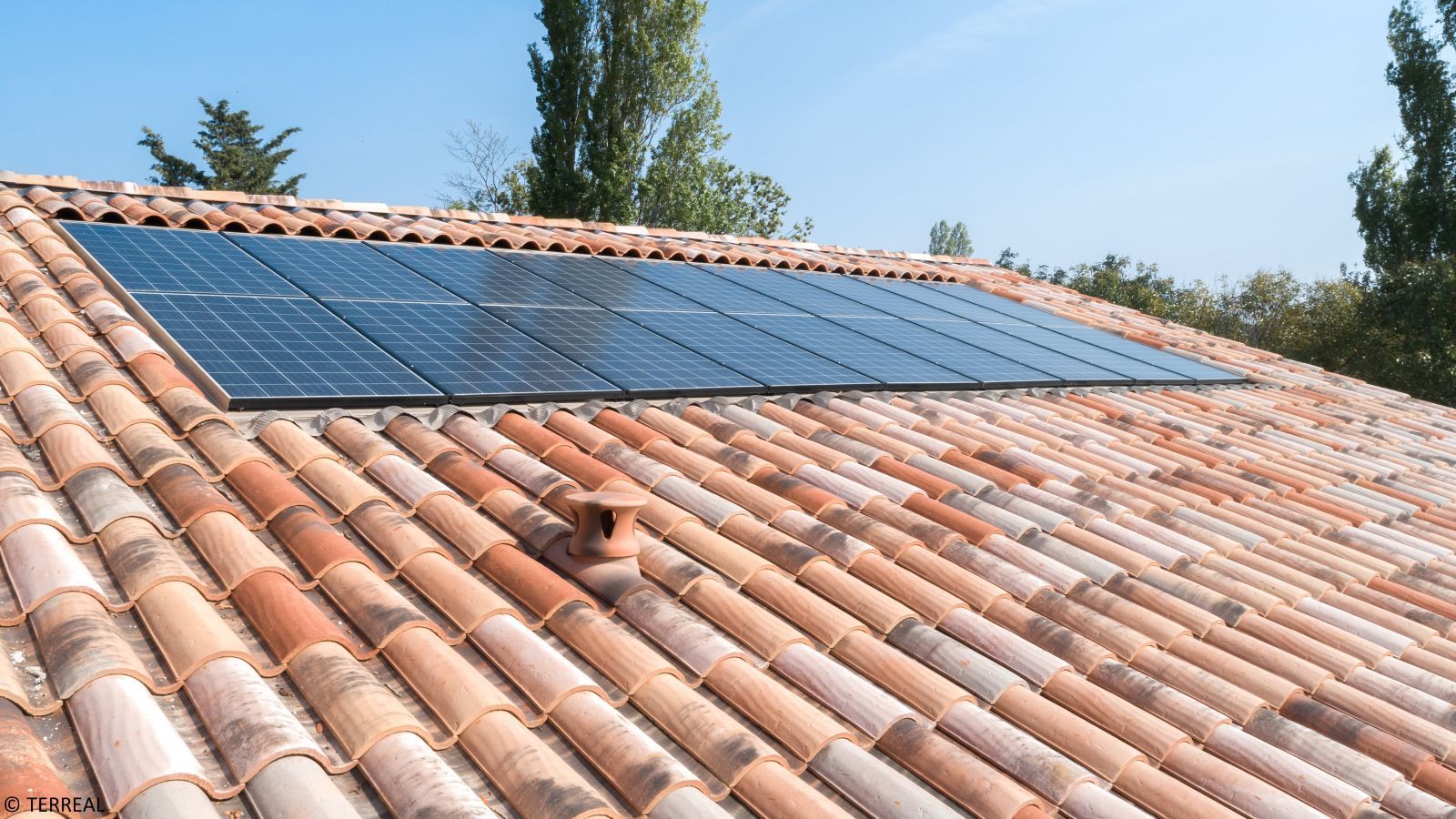 Toiture de tuiles rouges, oranges avec des panneaux photovoltaïques