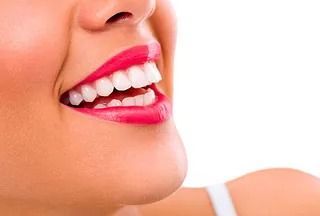 Un primer plano de la sonrisa de una mujer con dientes blancos y lápiz labial rojo.