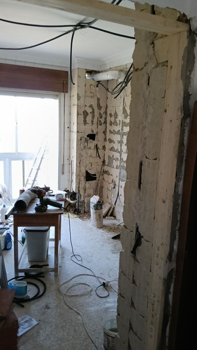 Demolición interior de una habitación. Pared de ladrillos a la vista, cables y materiales de construcción visibles.