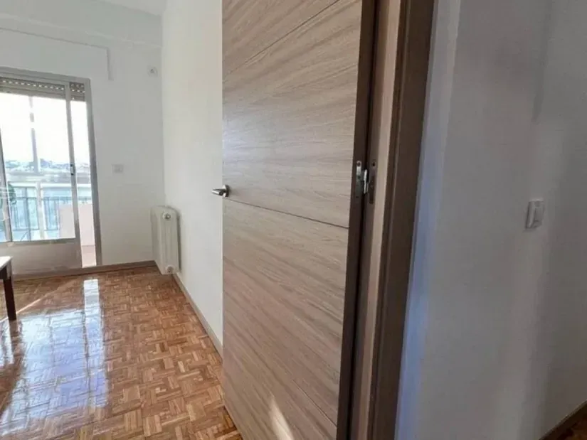 Un pasillo en una casa con piso de madera y una puerta de madera.