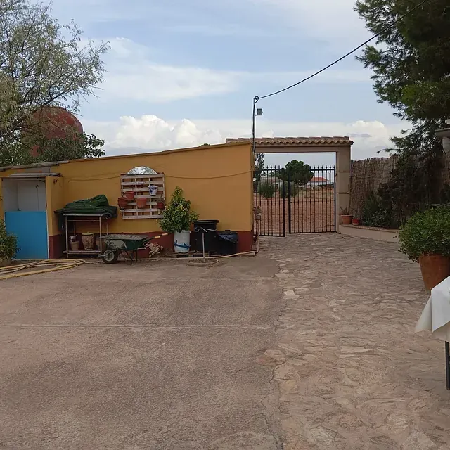 Un área cercada con un edificio amarillo al fondo.