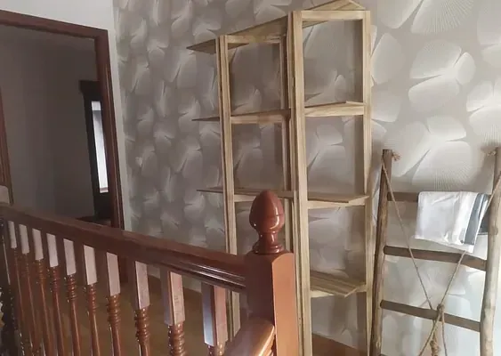 Una escalera con barandilla de madera y estantes en la pared.