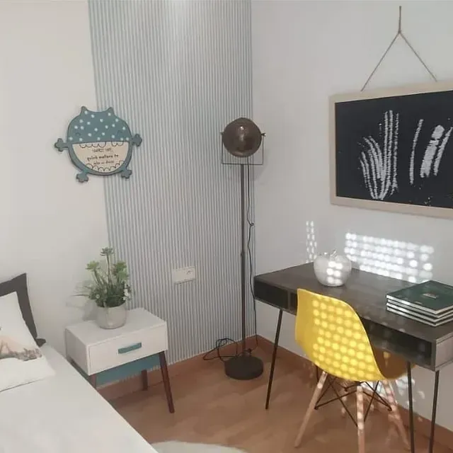 Un dormitorio con un escritorio y una silla amarilla.