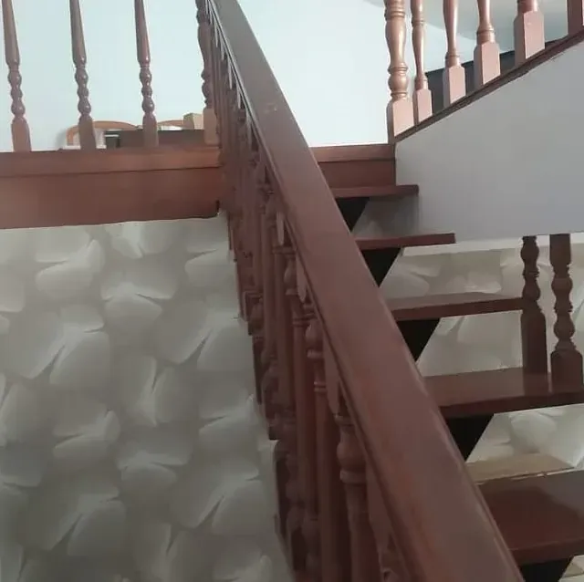 Una escalera con barandilla de madera que sube al segundo piso.