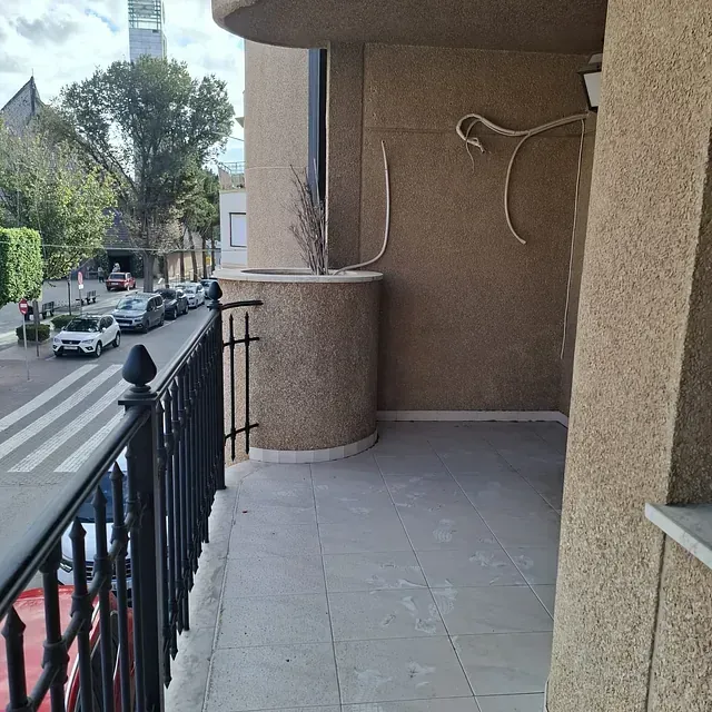 Un balcón con vistas a una calle con coches aparcados en él.