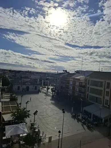 El sol brilla a través de las nubes sobre una plaza de la ciudad.