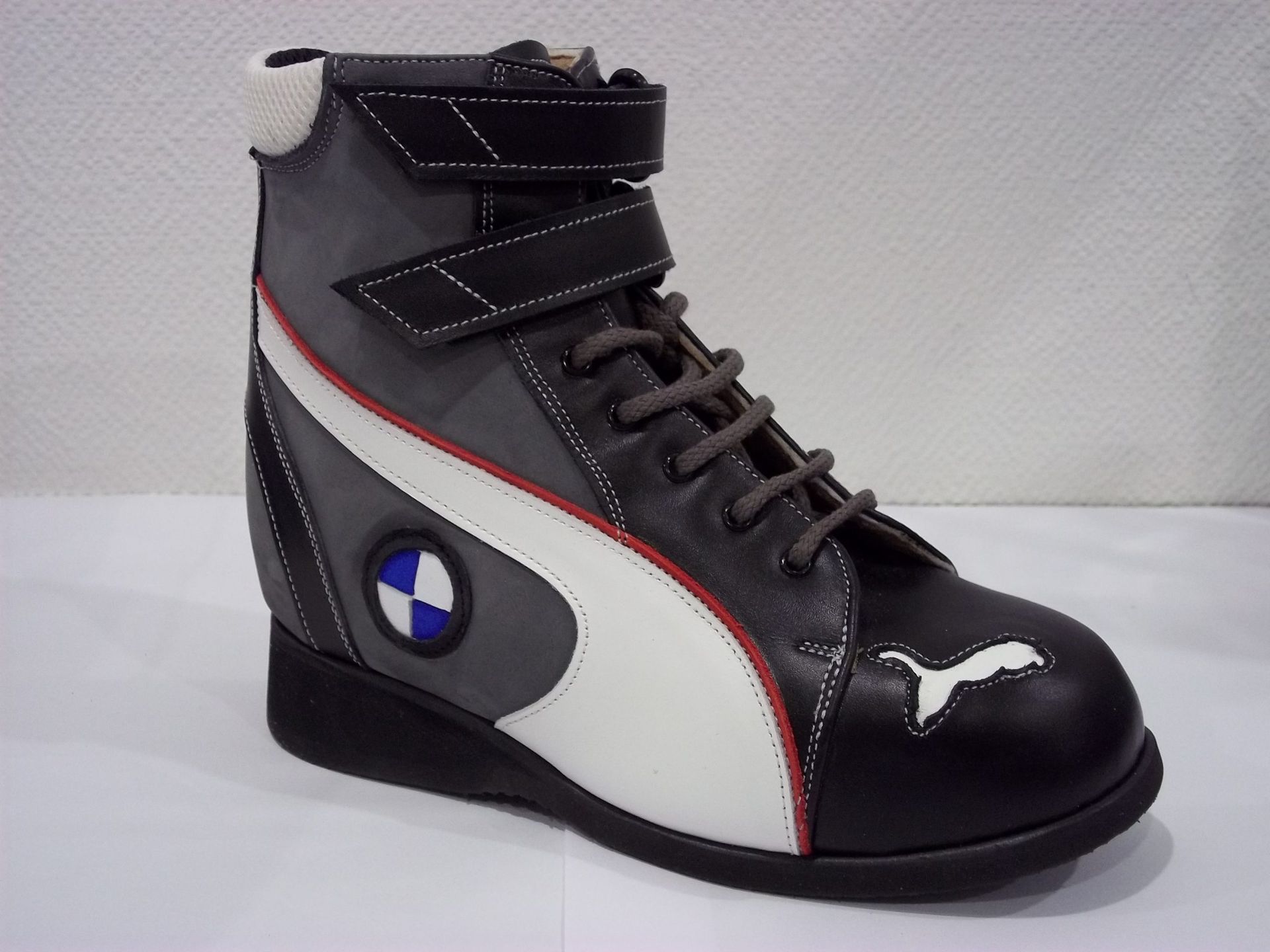 Baskets montantes noires avec des détails blancs, gris et rouges et un logo style BMW sur le côté