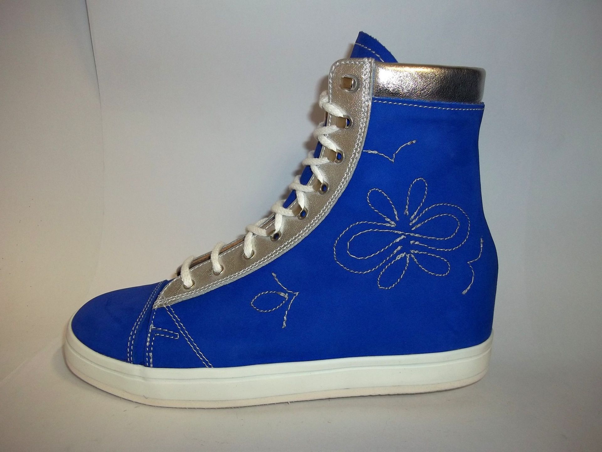 Baskets montantes bleues à lacets blancs et bordure argentée sur fond blanc