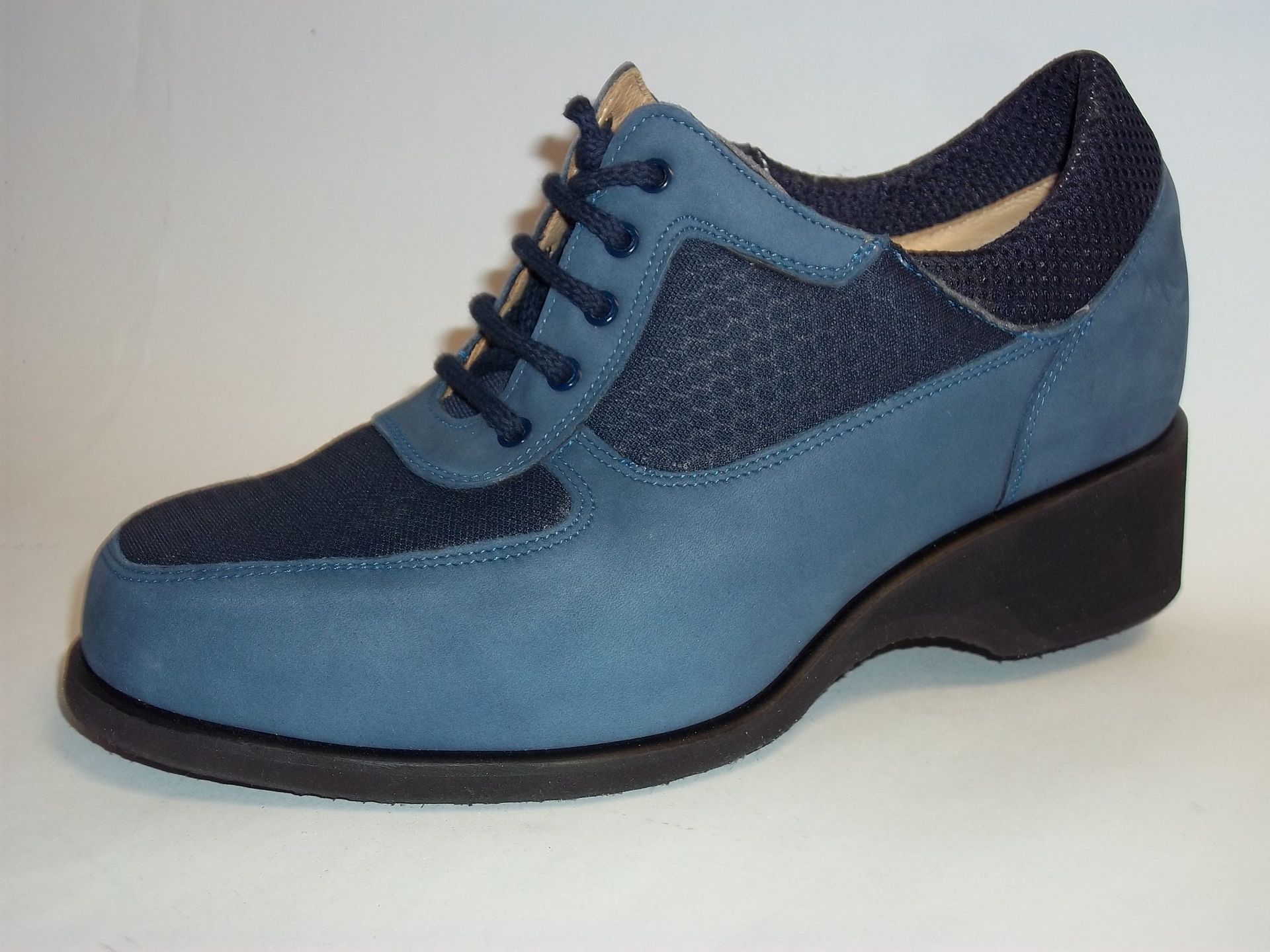 Chaussure Oxford à lacets en daim bleu avec semelle noire sur fond blanc