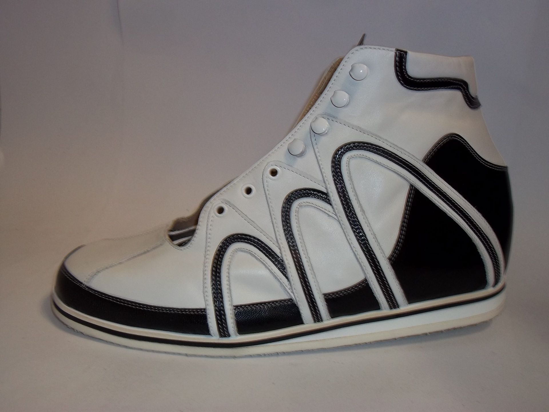 Baskets montantes blanches avec des accents noirs sur fond uni