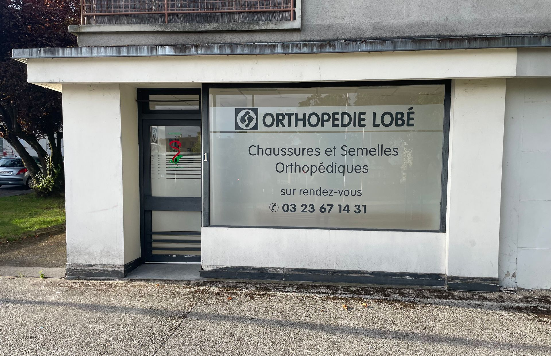 Un groupe de personnes se tient à l'extérieur, devant un bâtiment ; certaines portent des chemises blanches.