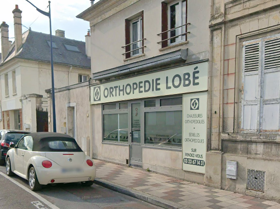 Un groupe de personnes se tient à l'extérieur, devant un bâtiment ; certaines portent des chemises blanches.