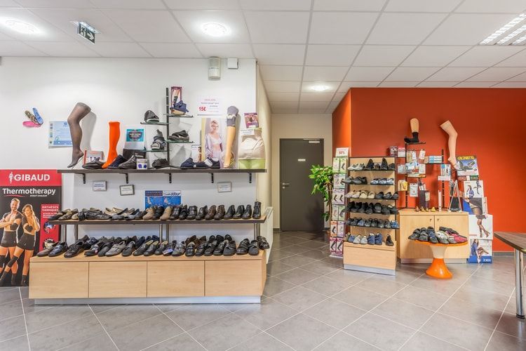 Intérieur d'un magasin de chaussures et de vêtements avec des étagères de chaussures, d'accessoires et des murs d'exposition orange.