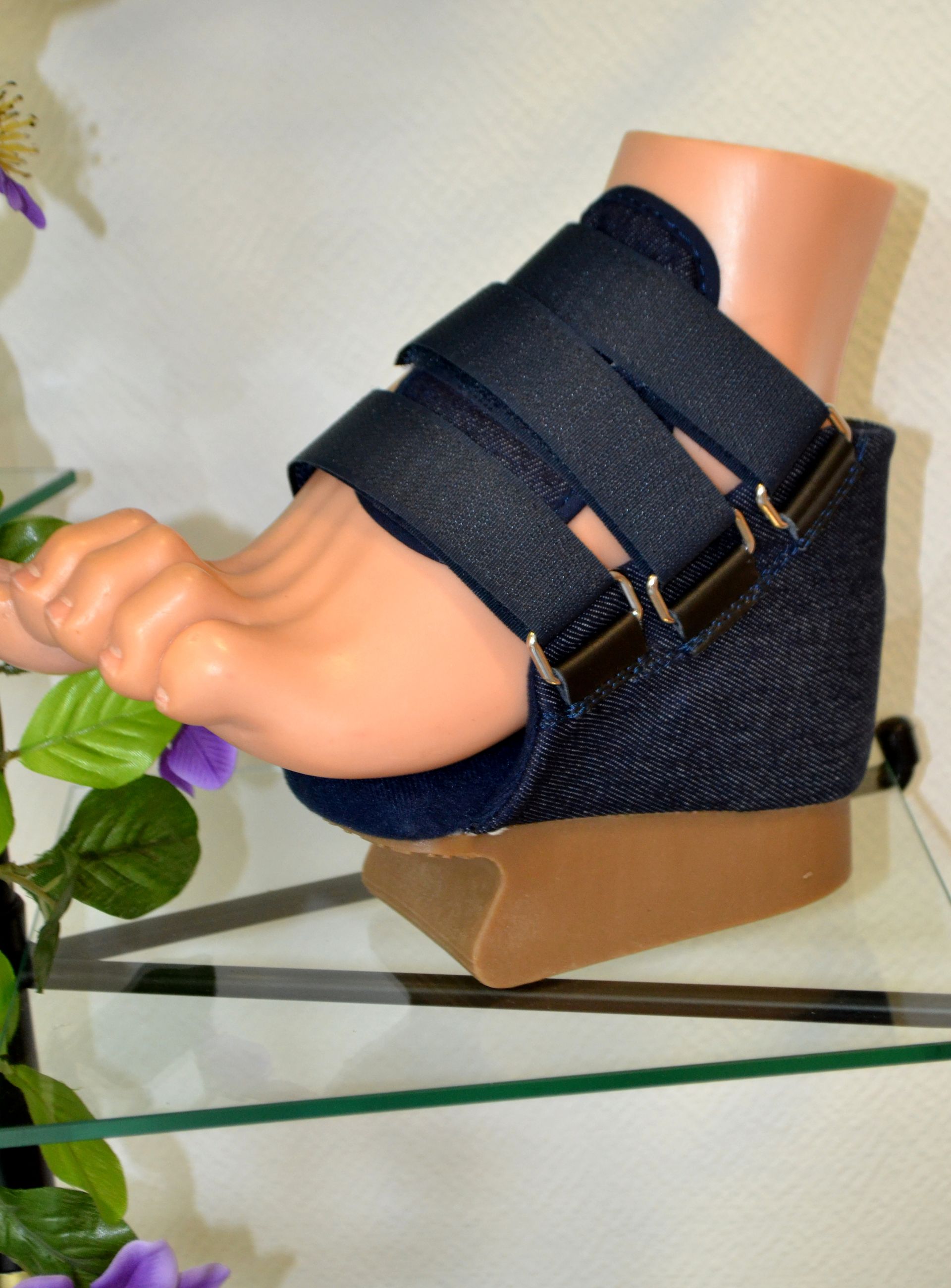 Un pied portant une attelle bleu marine et une cale de soutien beige sur un présentoir