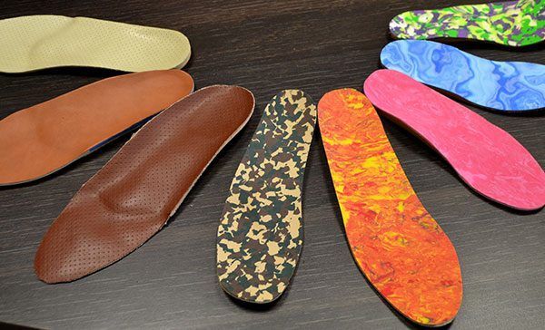 Semelles intérieures de chaussures colorées à motifs assortis disposées sur une table sombre