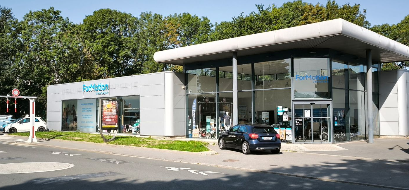 Un groupe de personnes se tient à l'extérieur, devant un bâtiment ; certaines portent des chemises blanches.