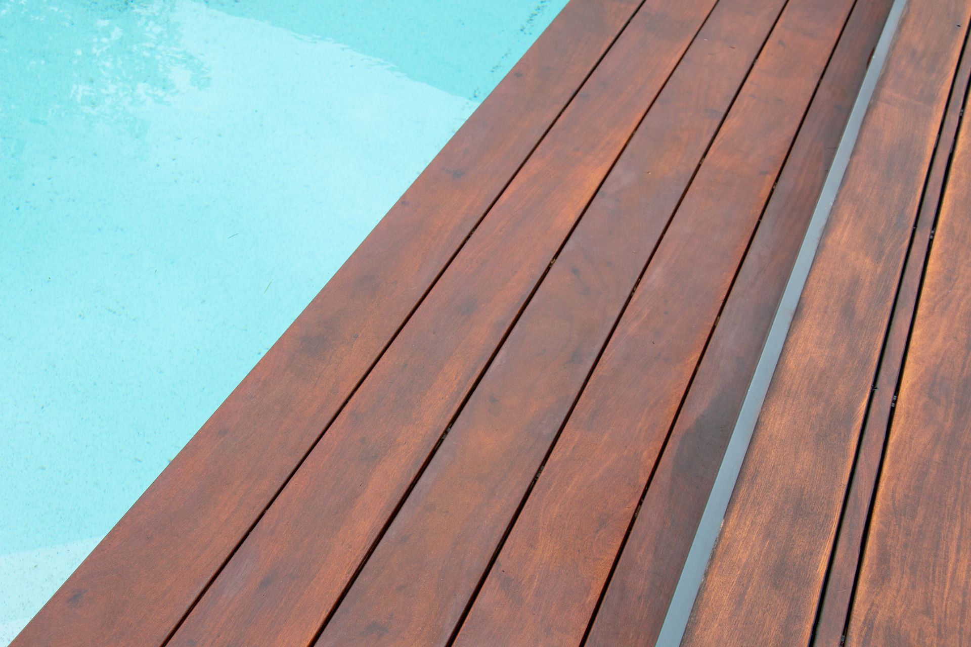 Plancher en bois brun sombre au bord d'une piscine