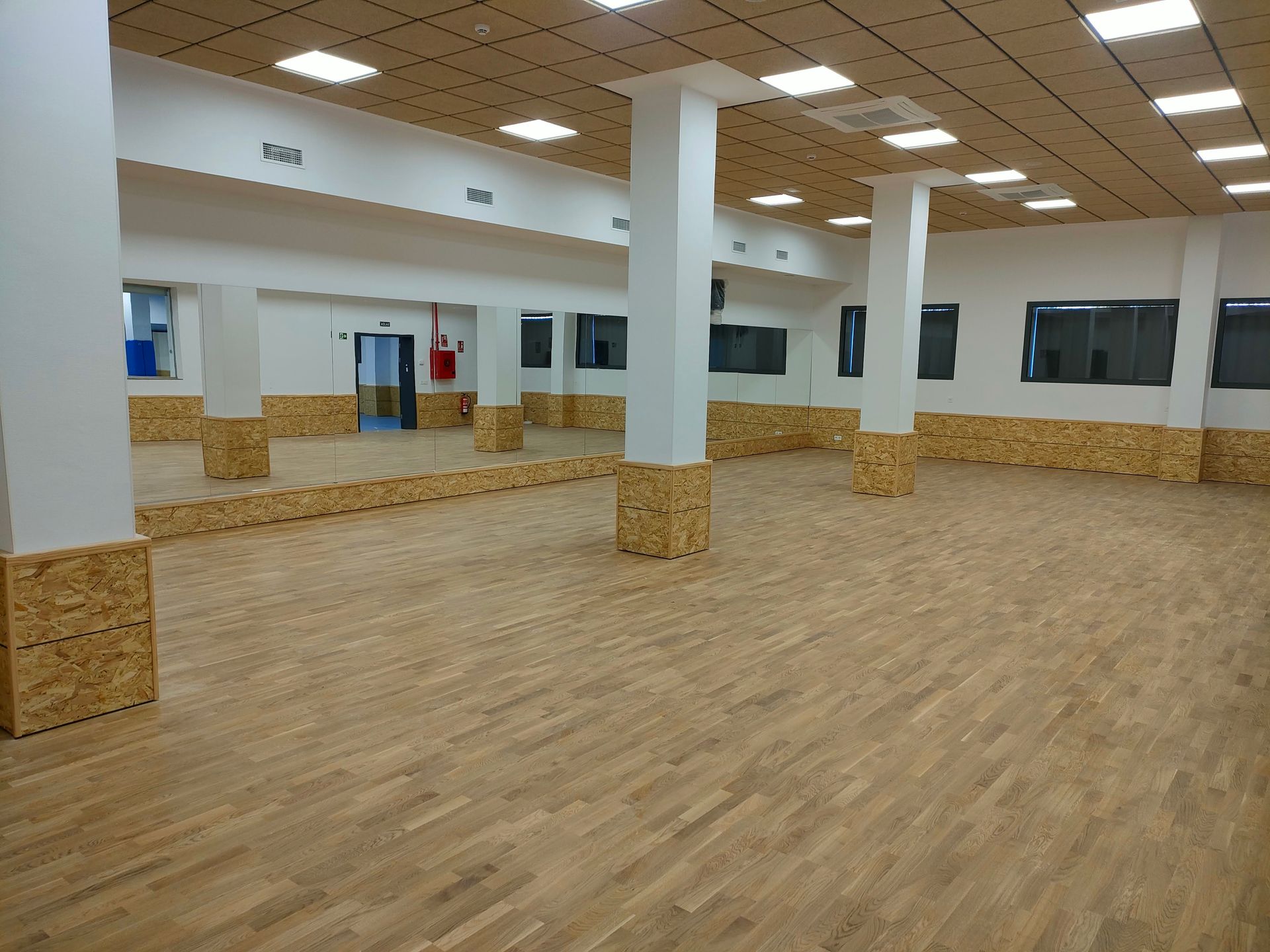 Una gran habitación vacía con suelos de madera y espejos.