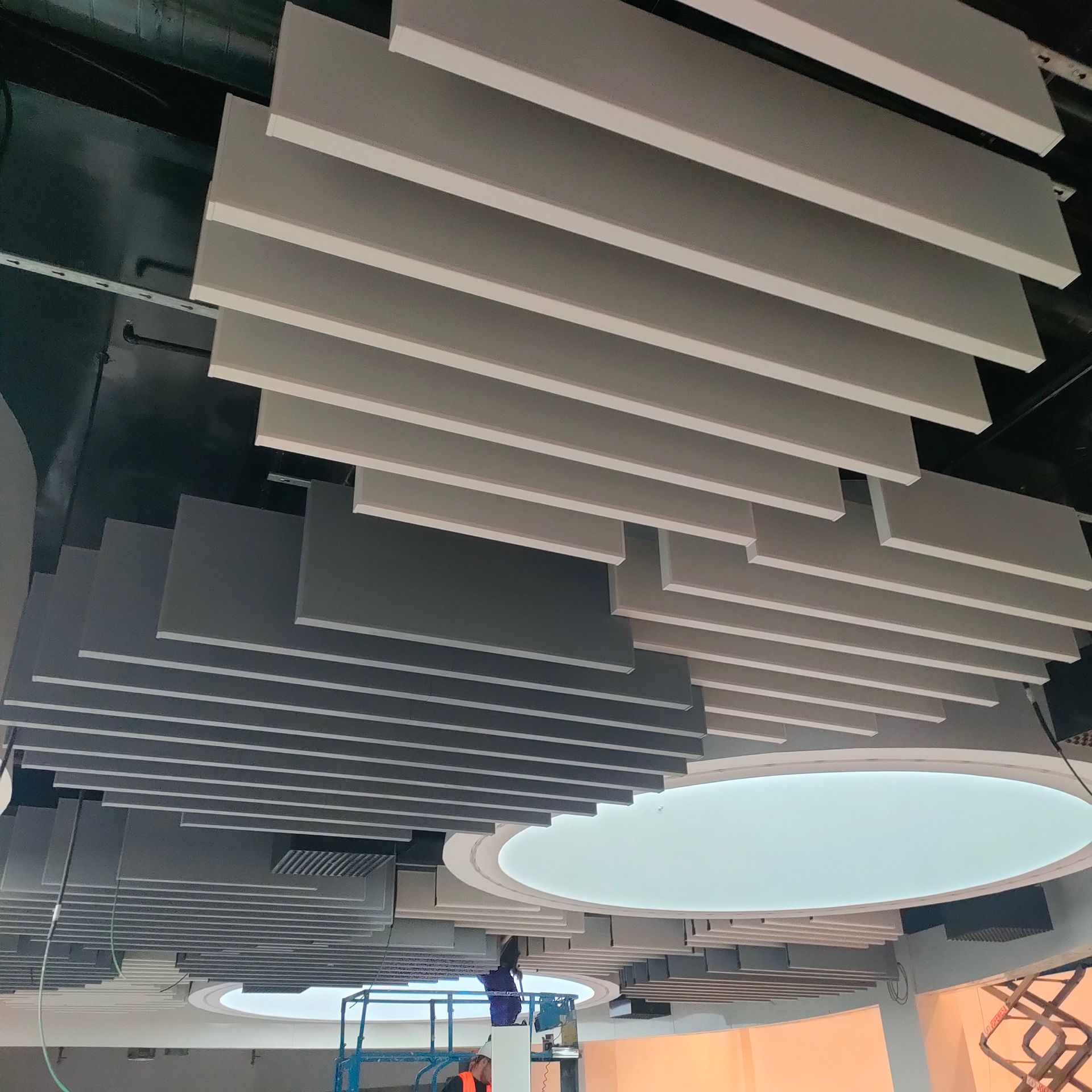 Un hombre está de pie en una escalera mirando hacia el techo de un edificio.