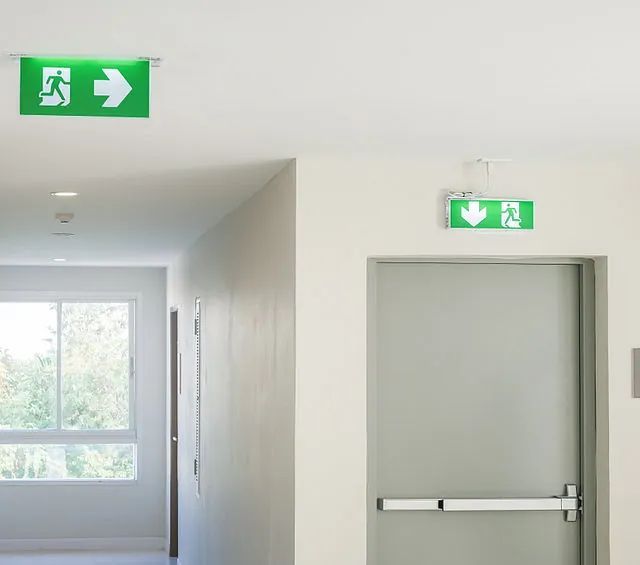 Un pasillo con una señal de salida verde encima de la puerta.