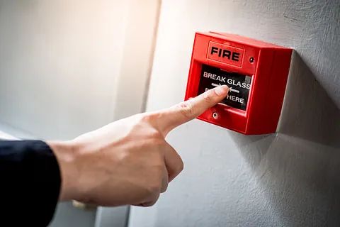 Una persona está presionando un botón de alarma contra incendios con su dedo.