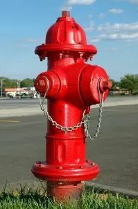 Una boca de incendios roja está encadenada al costado de la carretera.