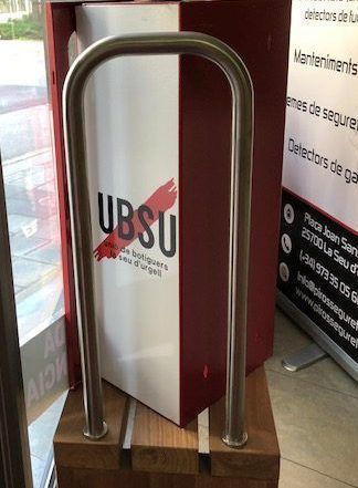 Una caja roja y blanca con un mango de acero inoxidable está colocada encima de un bloque de madera.