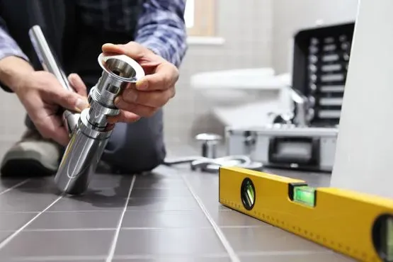 Un fontanero está arreglando una tubería en un baño.