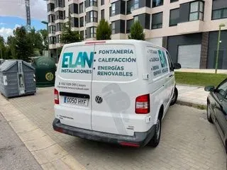Una camioneta blanca está estacionada al costado de la carretera frente a un edificio.