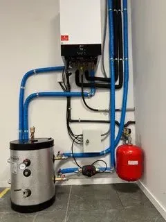 Una habitación con caldera, tanque de agua y tuberías.