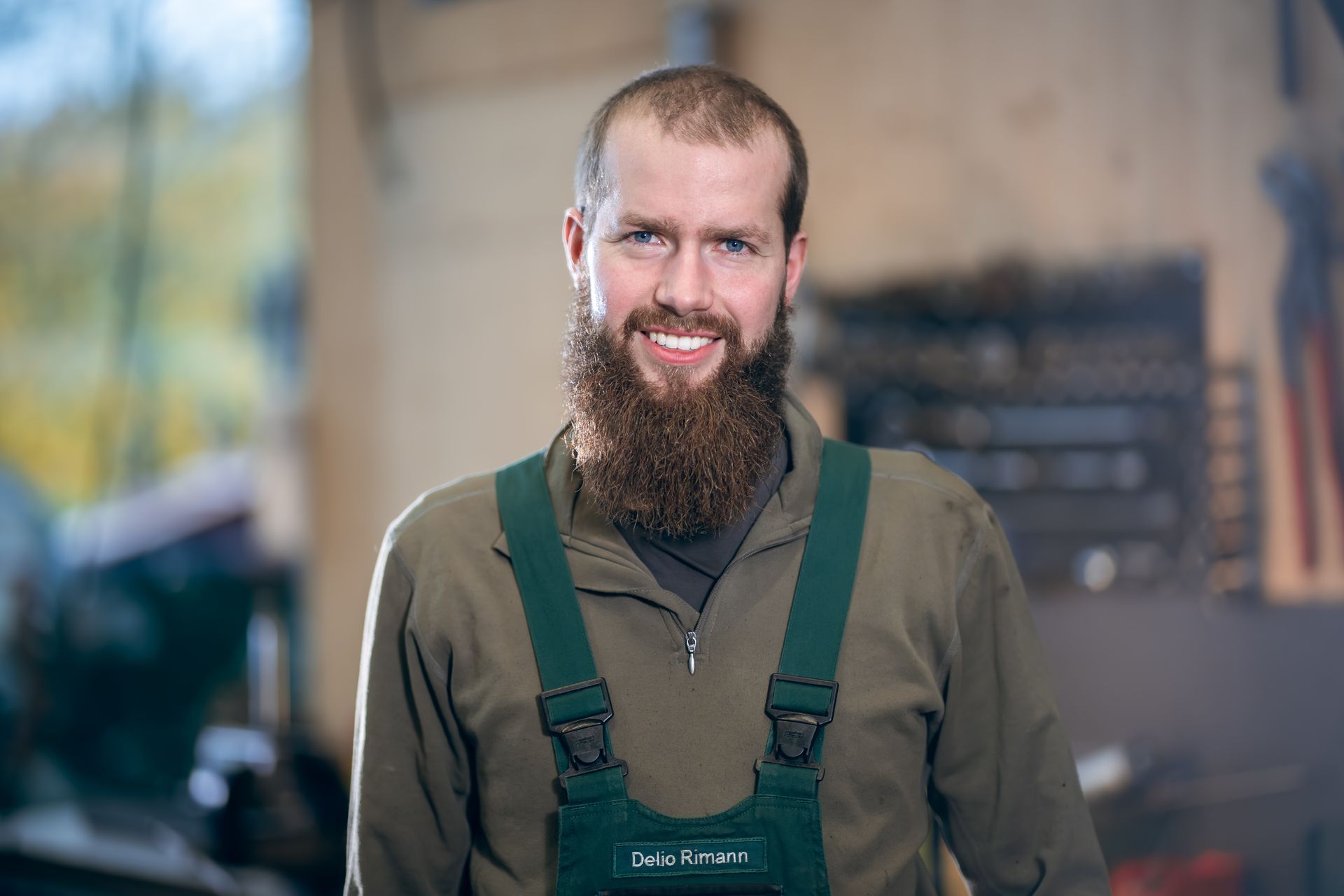 Ein Mechaniker arbeitet in einer Werkstatt an einem orangefarbenen Traktor und liegt dabei auf dem Boden.