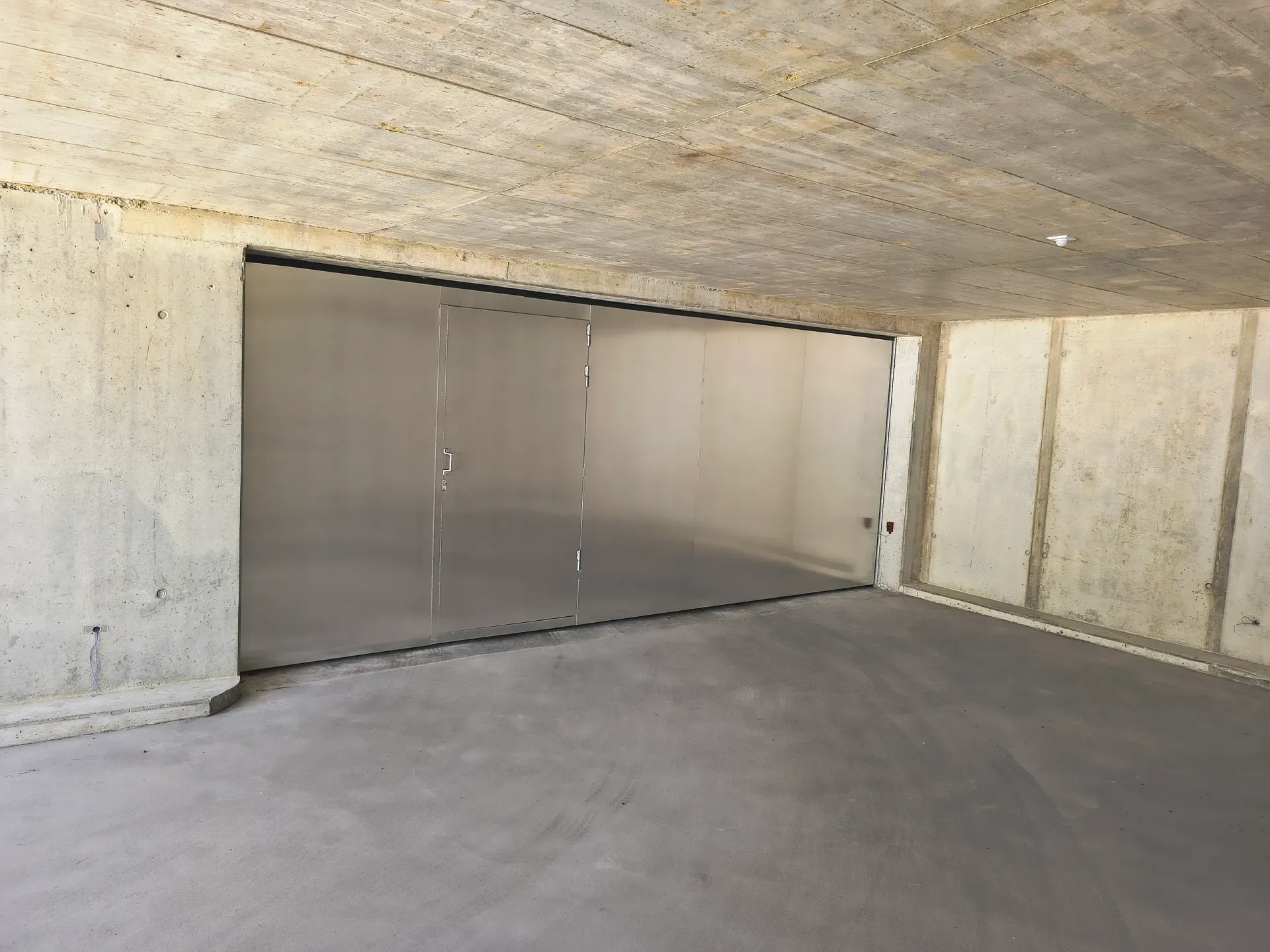 Betonraum mit lichtdurchlässigen Paneelen in der Öffnung sowie Wänden, Boden und Decke aus Beton.