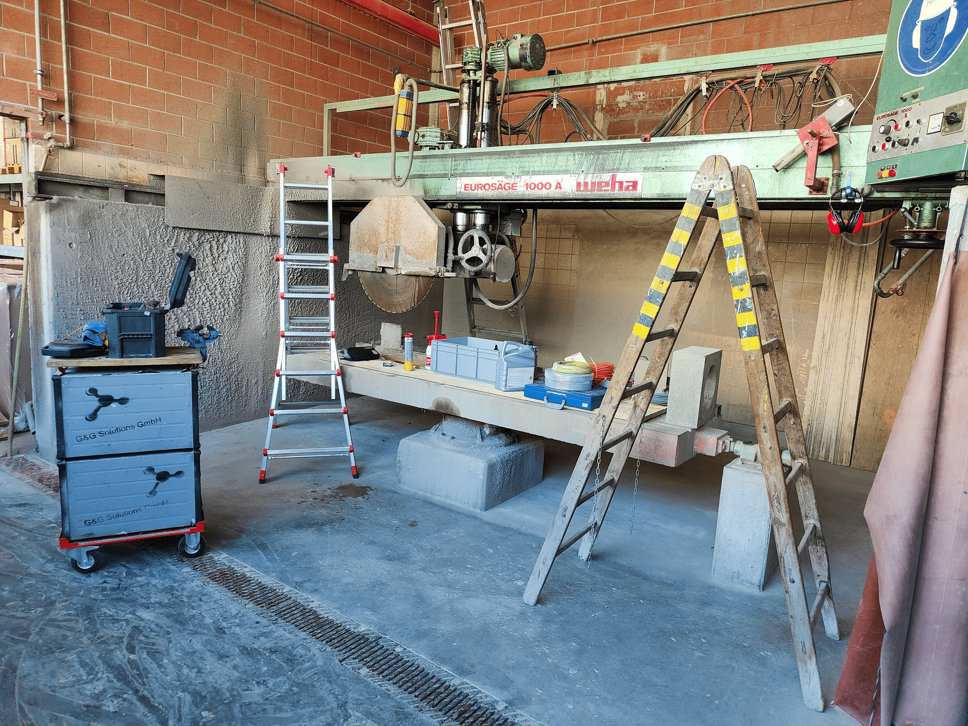 In einem Raum steht neben einer Maschine eine Leiter.
