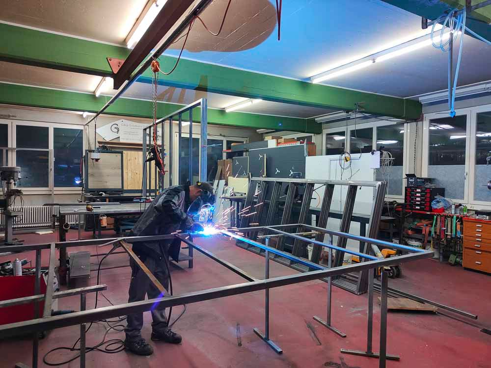 Schweißer in einer Werkstatt, Schweißen Metallrahmen. Funken fliegen.