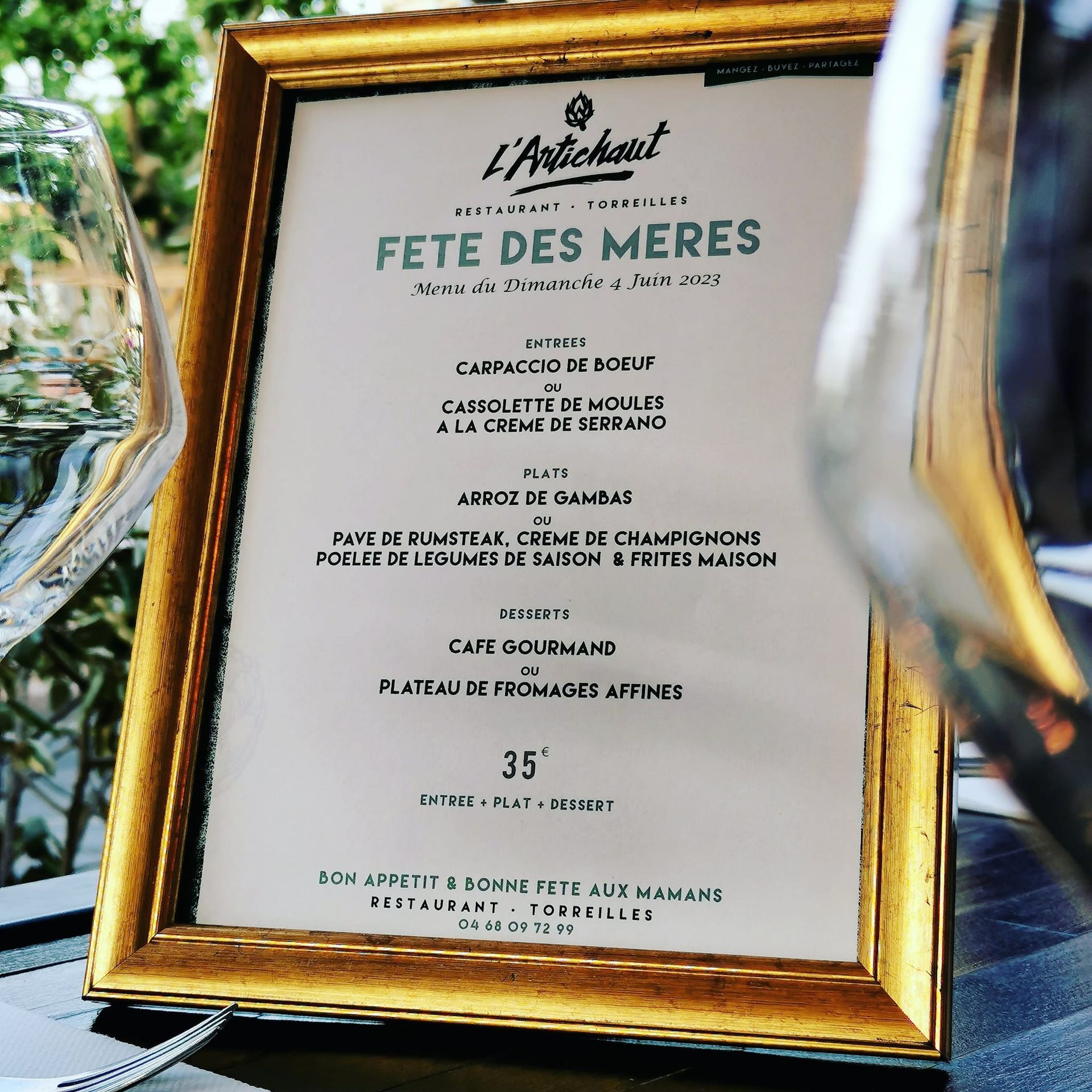 Menu de la fête des mères encadré dans un support doré devant le restaurant