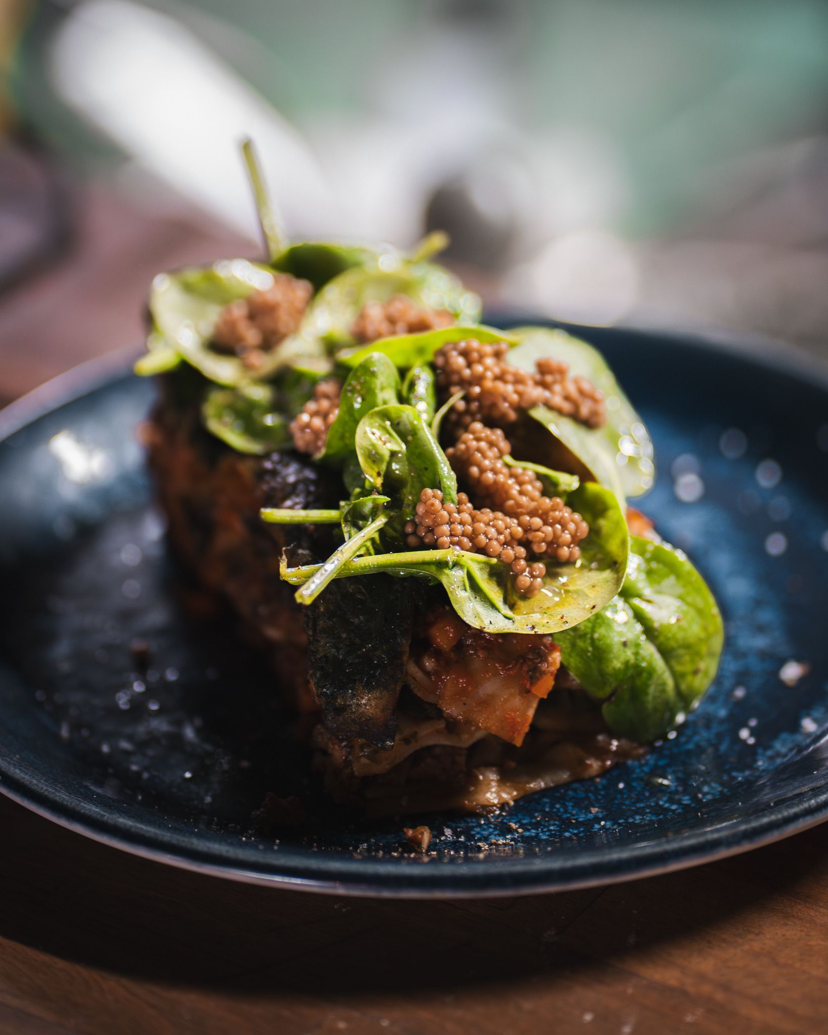 Gros plan sur un plat gastronomique composé de poisson poêlé garni de verdure fraîche, présenté sur une assiette bleu foncé