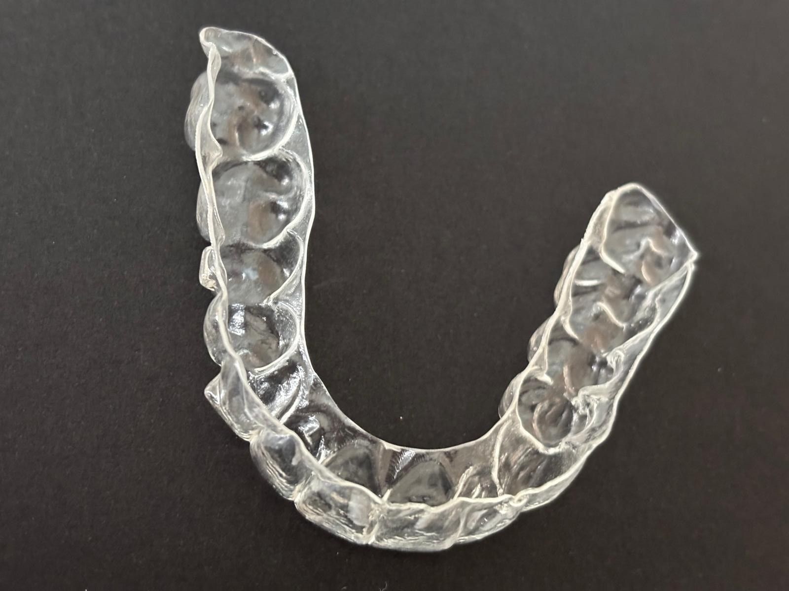 Eine Hand mit blauem Handschuh hält einen leuchtenden Zahnquerschnitt. Blauer Hintergrund mit Lichtspuren.